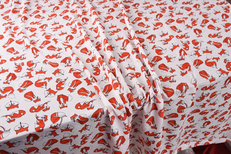 May include: White fabric with a repeating pattern of red foxes. The foxes are stylized and facing different directions.