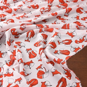 May include: White fabric with a repeating pattern of red foxes. The foxes are drawn in a simple, cartoon style.
