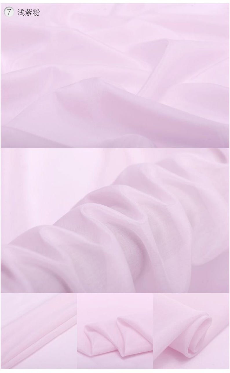 May include: A close-up of a pale pink sheer fabric. The fabric is smooth and has a delicate drape. The fabric is folded in several places, showing the texture and translucency.
