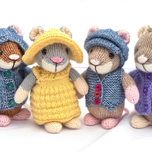 Op de afbeelding: Vier handgemaakte gebreide muizenpoppen. Elke muis draagt een andere outfit: een blauwe jas met capuchon, een gele jurk en hoed, een blauw vest en pet, en een paars vest. De muizen hebben roze oren en neuzen.