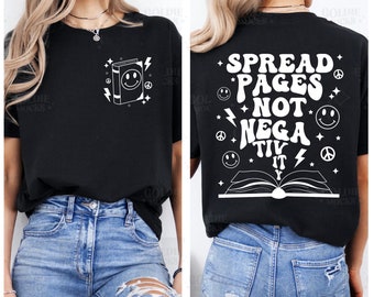 Può includere: Maglietta nera con una grafica bianca di un libro con un'emoticon sorridente sul davanti e il testo "Spread Pages Not Negativity" sul retro.