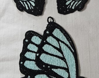 May include: Three embroidered butterfly patches. The butterflies have black outlines and light blue wings. The largest butterfly is in the center, with two smaller butterflies above it. Each patch has a small loop at the top.