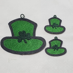 May include: Three green felt shamrock hats with black outlines. The hats are different sizes and are perfect for a St. Patrick's Day craft project.