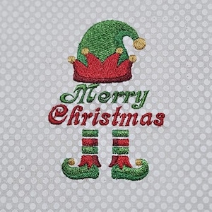 May include: Embroidered Christmas design featuring an elf hat, red collar, and green and red striped legs. The words "Merry Christmas" are embroidered in green and red. The background is a light gray fabric with white polka dots.