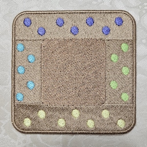 Può includere: Un sottobicchiere quadrato marrone con un centro marrone e un bordo di punti blu, verdi e gialli.