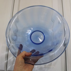 May include: A large, light blue glass bowl with a wavy rim. The bowl is clear and has a slight blue tint.