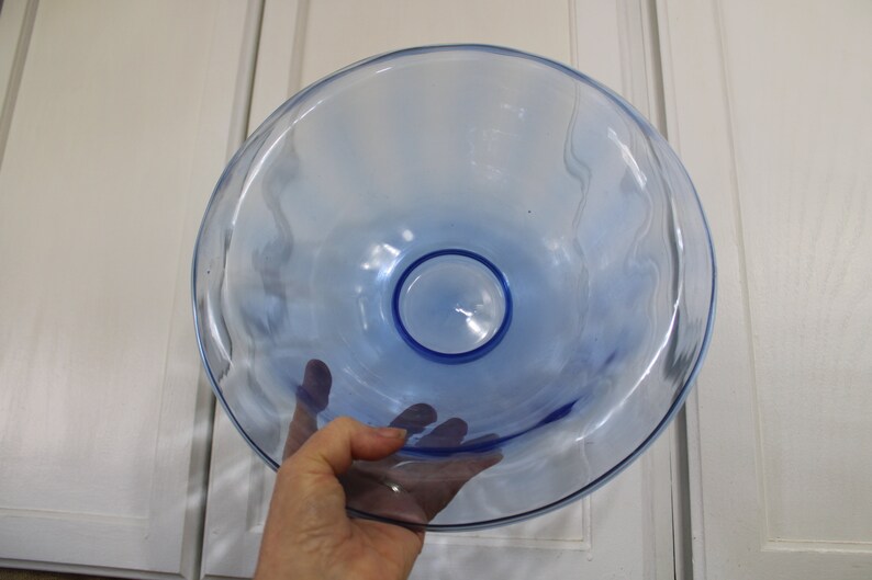May include: A large, light blue glass bowl with a wavy rim. The bowl is clear and has a slight blue tint.