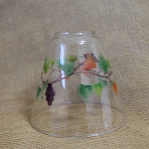 May include: A clear glass lampshade with a painted design of green leaves, orange and purple grapes, and a vine.