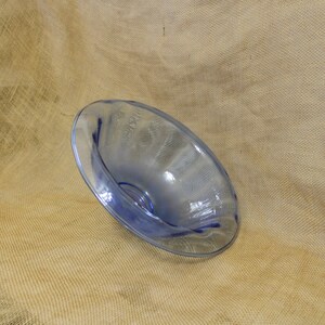 May include: A light blue glass bowl with a wavy rim. The bowl is sitting on a brown burlap surface.