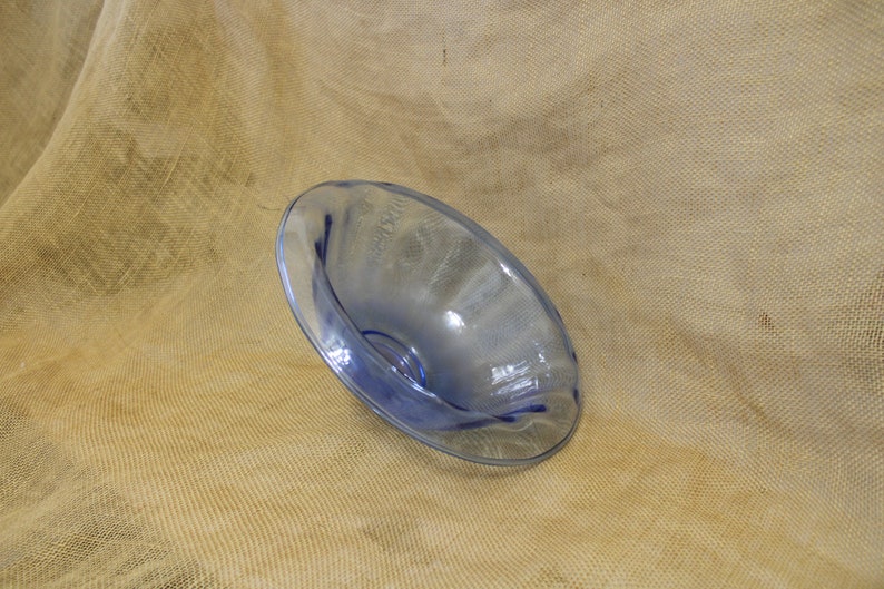 May include: A light blue glass bowl with a wavy rim. The bowl is sitting on a brown burlap surface.