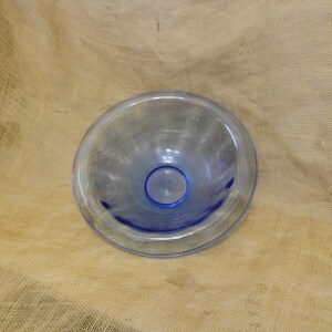 May include: A clear glass bowl with a blue rim. The bowl has a textured surface and is slightly iridescent.