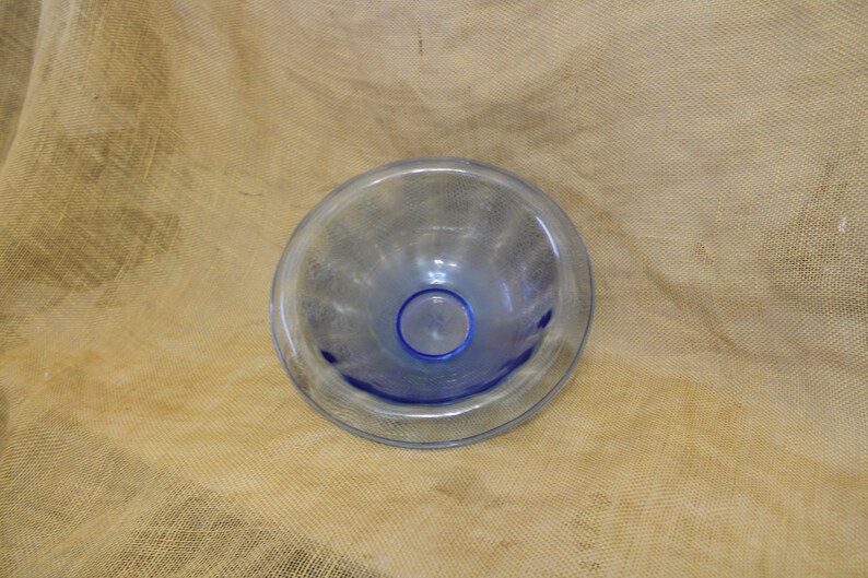 May include: A clear glass bowl with a blue rim. The bowl has a textured surface and is slightly iridescent.