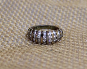 May include: A gold and silver ring with a row of clear stones set in a band.