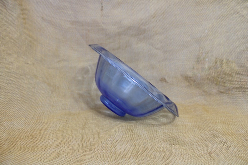 May include: A blue glass bowl with a scalloped rim and a pedestal base.