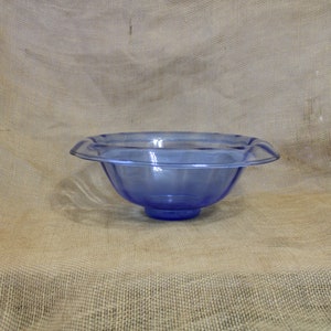 May include: A large, clear blue glass bowl with a scalloped rim. The bowl is sitting on a burlap background.