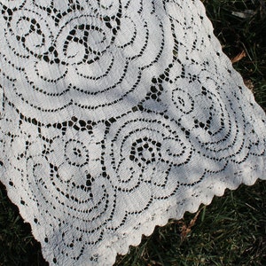 May include: White crocheted lace table runner with a delicate floral pattern. The runner is made of a fine, lightweight material and has a scalloped edge.