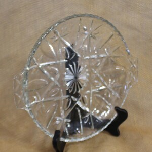 May include: A clear glass serving dish with a starburst pattern and two handles. The dish is on a black stand.