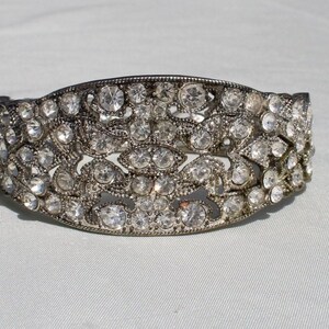 May include: A silver bracelet with a delicate design featuring a row of clear rhinestones.
