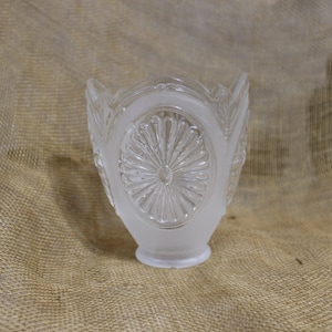 May include: A frosted glass lampshade with a decorative, circular pattern. The shade has a scalloped edge and a frosted finish.