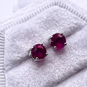 May include: A pair of ruby red stud earrings in a white velvet jewellery box.