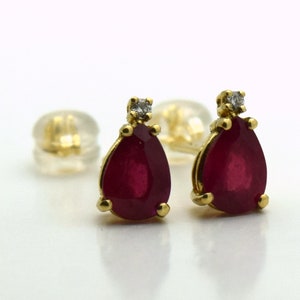 May include: A pair of gold earrings featuring pear-shaped ruby gemstones, each with a single diamond accent.
