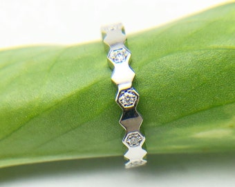 May include: A silver ring with a hexagonal design and small clear stones set into each hexagon.