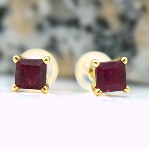 May include: A pair of gold earrings with square-shaped ruby gemstones.