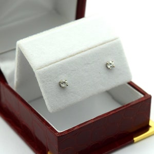 May include: A pair of diamond earrings in a red velvet jewelry box with a gold trim.