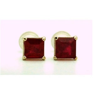 May include: A pair of gold earrings with square red gemstones.