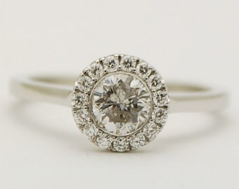 May include: A silver ring with a round, clear diamond center stone surrounded by a halo of smaller diamonds.