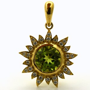 May include: A gold pendant featuring a green gemstone surrounded by a halo of small diamonds. The pendant is shaped like a sun with rays.