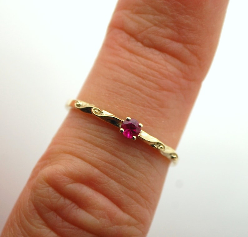Peut inclure: Une bague en or avec un motif d&eacute;licat en spirale et une seule pierre rouge brillante.