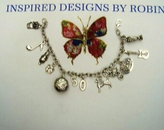 May include: A silver charm bracelet with a variety of charms, including a butterfly, a musical note, a guitar, a number 50, and a poodle. The bracelet is on a white background.