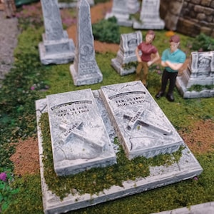 May include: Two grey stone grave markers with engraved crosses and dates. The text on the left marker reads "LORENA  IMMAC  JAN. 18 1858  SEPT. 21 1904  MOTHER". The text on the right marker reads "ELLENORA  M.  FEB. 25 1880  AUG. 12 1923  FATHER".
