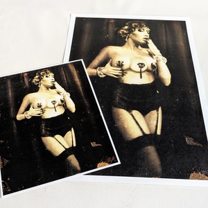 May include: A black and white photograph of a woman wearing a black bra and suspender belt with a vintage style. She is posing with her hand on her chin and looking to the side.