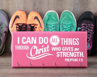 May include: Pink wooden shoe rack with hooks and the text "I can do all things through Christ who gives me strength. Philippians 4:13". There are six pairs of running shoes in the background.