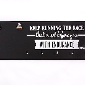 May include: Black wooden medal holder with the text "KEEP RUNNING THE RACE &mdash;that is set before you&mdash; WITH ENDURANCE HEBREWS 12:1" in white lettering. The holder has two clips and five hooks.