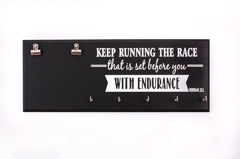 May include: Black wooden medal holder with the text "KEEP RUNNING THE RACE &mdash;that is set before you&mdash; WITH ENDURANCE HEBREWS 12:1" in white lettering. The holder has two clips and five hooks.