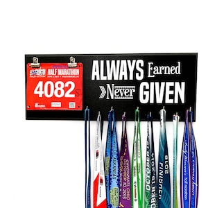 May include: A black wooden medal display with the text "ALWAYS Earned >>Never GIVEN". A red race bib with the number "4082" is attached to the display.  The display has hooks for hanging medals, and several colorful medals are hanging from the hooks.