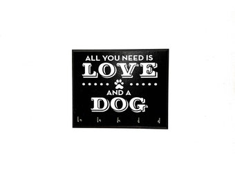 May include: Black key holder with the text "All you need is love and a dog" in white lettering with a paw print between the words "love" and "and".