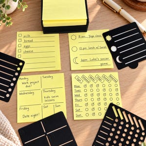 May include: A stack of yellow sticky notes in a black holder, accompanied by four black plastic stencils and four yellow sticky notes with printed checklists, schedules, and habit trackers, including text like milk, bread, eggs, cheese, and yoga class.