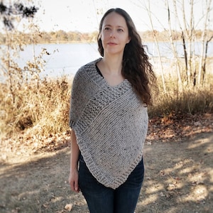 May include: A gray knit poncho with a V-neck design. The poncho is worn over a black top and dark blue jeans. The model is wearing black boots. The word "ORNUTE" is printed at the bottom of the image.