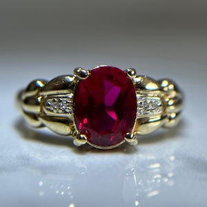 Peut inclure: Une bague en or avec une grande pierre de rubis ovale et de petits diamants sertis dans la bande.