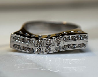 May include: A silver ring with two rows of small, clear diamonds set in a curved band.