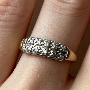 May include: A gold band ring with a double row of small, clear stones.