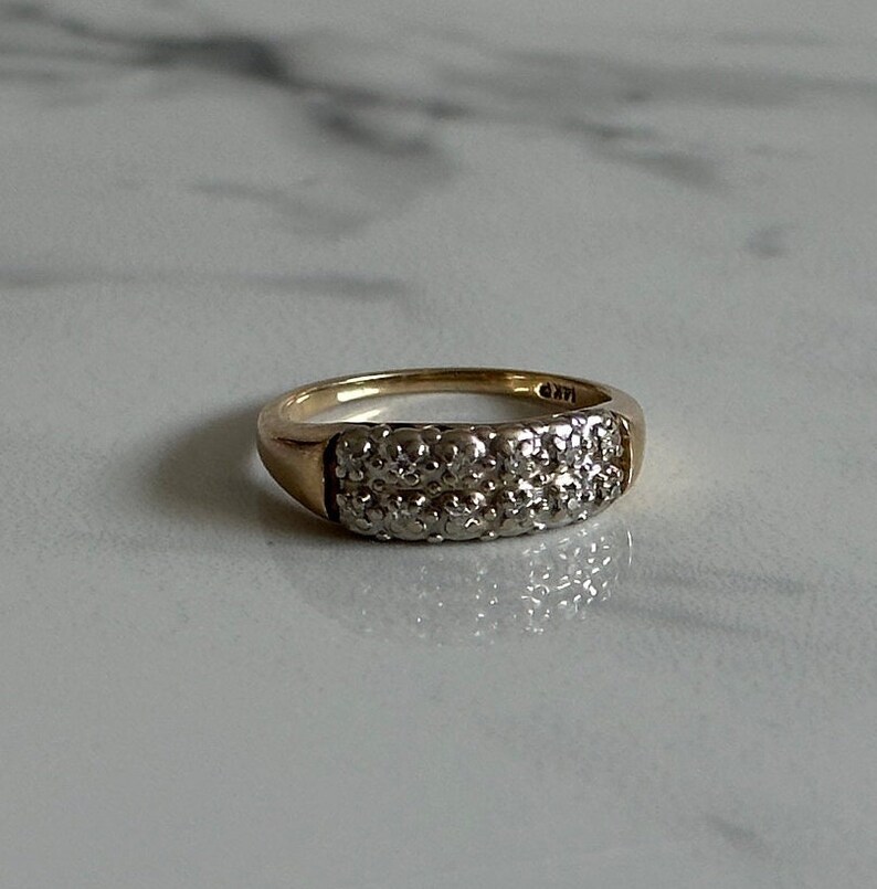 May include: A gold band ring with a double row of small diamonds.