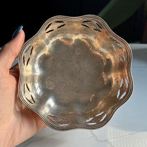 May include: A silver, scalloped, decorative dish with a cut-out design around the edge. The dish is slightly tarnished.
