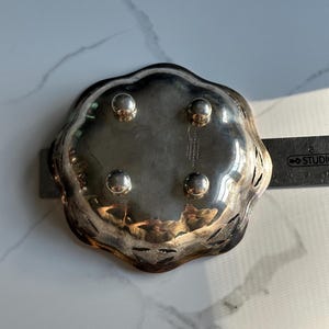 May include: Silver bowl with a scalloped edge and a decorative cut-out design. The bowl has four feet and is approximately 5 inches in diameter.