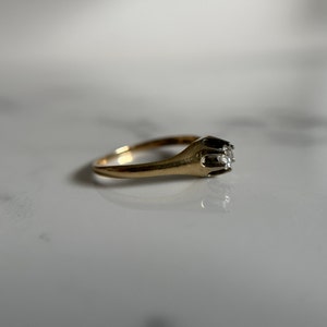 May include: A gold ring with a single diamond set in a prong setting.