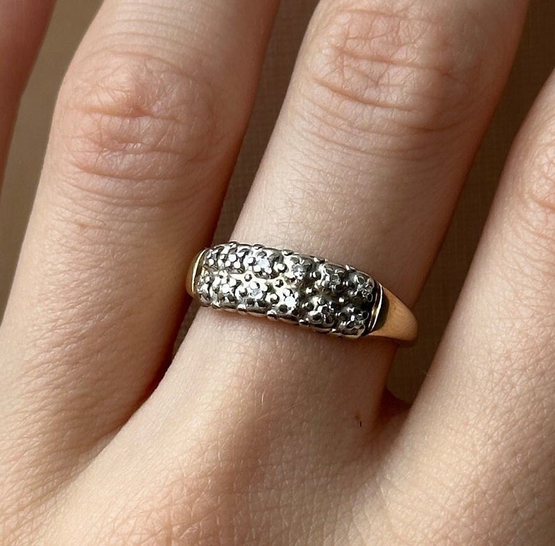 May include: A gold band ring with a double row of small, clear stones.